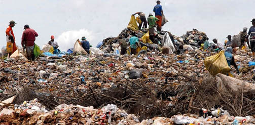 Waste pickers on top of a large waste dump in Brazil, collecting plastic bottles for recycling.