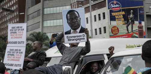 A man holds a placard featuring Emmerson D. Mnangagwa, as people gathered in the city centre to celebrate what they hoped was soon to be the end of Robert Mugabe's 37 year rule.