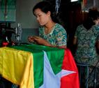 Woman sewing a flag in Myanmar A woman makes a new Burmese flag in a workshop in Yangon. The Burmese government introduced the new flag in the lead up to the elections in 2010.