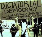US Protester with Dictatorial Democracy sign This was written on an actual voting booth. It reads, "DICTATORIAL DEMOCRACY... is where you have FREEDOM of SPEECH but the ADMINISTRATION doesn't LISTEN. Credit: The Prophet (CC BY 2.0)