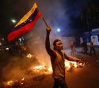 Protests in Venezuela An opposition demonstrators holds a Venezuelan flag in front of a burning barricade during a protest against President Nicolas Maduro's government in Caracas February 15, 2014. Protesters gathered to demand the president's resignation, denouncing him over grievances ranging from political repression to daily issues such as inflation, shortages of basic products, and rampant crime.REUTERS/Jorge Silva.