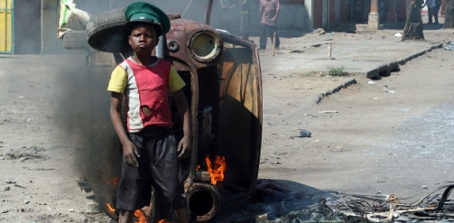 Boy stand by a burning car in the 2008 Mozambique riots.