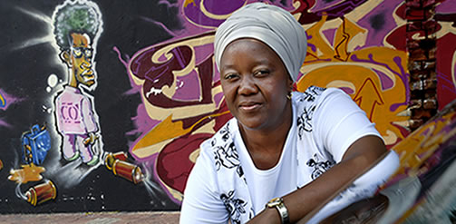 Taxi driver, Lena Mankope Mahalefa, leans on her cab in front of a graffiti-covered wall, in the crowded inner city of Johannesburg. Credit: Graeme Williams / Panos