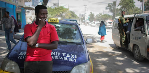 A driver of the Mogadishu Taxi Company waits for a fare outside the company's head office in the Somali capital Mogadishu, September 2013. Operating since the end of May in the city's dusty and once again bustling streets and thoroughfares, the MTC's distinctive yellow and purple cars offer customers taxi fares around Mogadishu at competitive rates and in the first 3 months of operations, the company has increased it's fleet of vehicles from an initial 25 to over 100. The company, according to one of it's drivers, also enables employment opportunities for Somalia's youth following two decades of conflict in the Horn of Africa nation that shattered a generation. AU-UN IST PHOTO / STUART PRICE