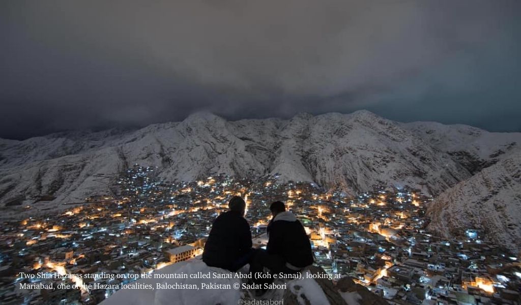 Two Shia Hazaras standing on top the mountain called Sanai Abad (Koh e Sanai), looking at Mariabad in Balochistan, Pakistan