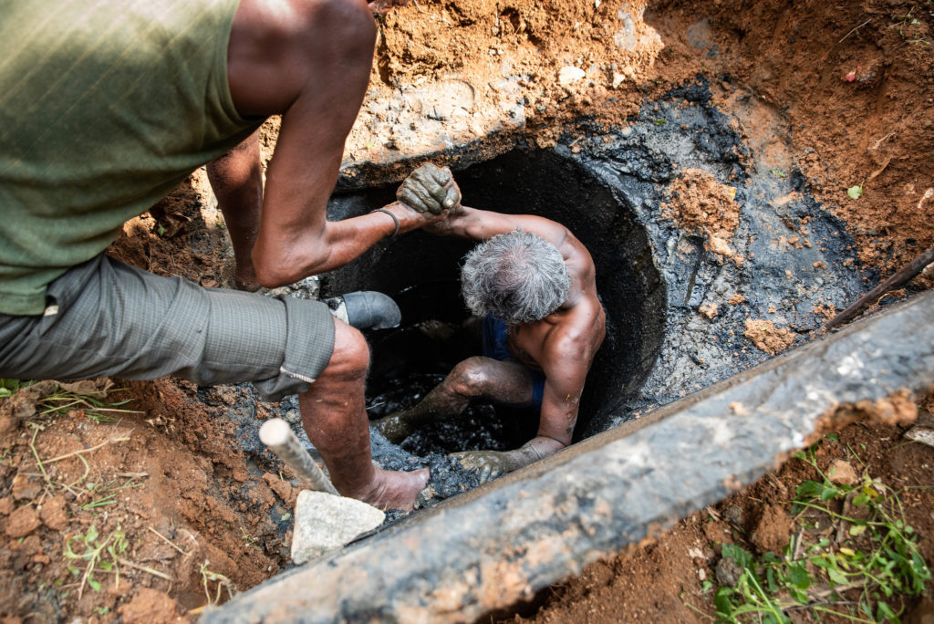 Sanitation workers manually emptying faecal sludge from pits in Bangalore, India