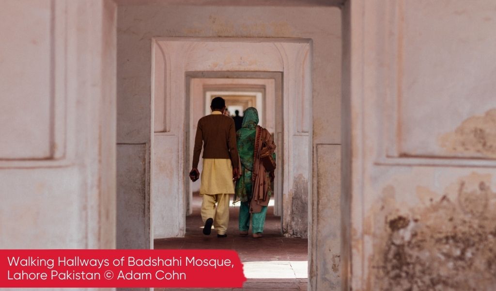 A man and a woman, seen from behind, walking down a Hallways of Badshahi Mosque, Lahore Pakistan