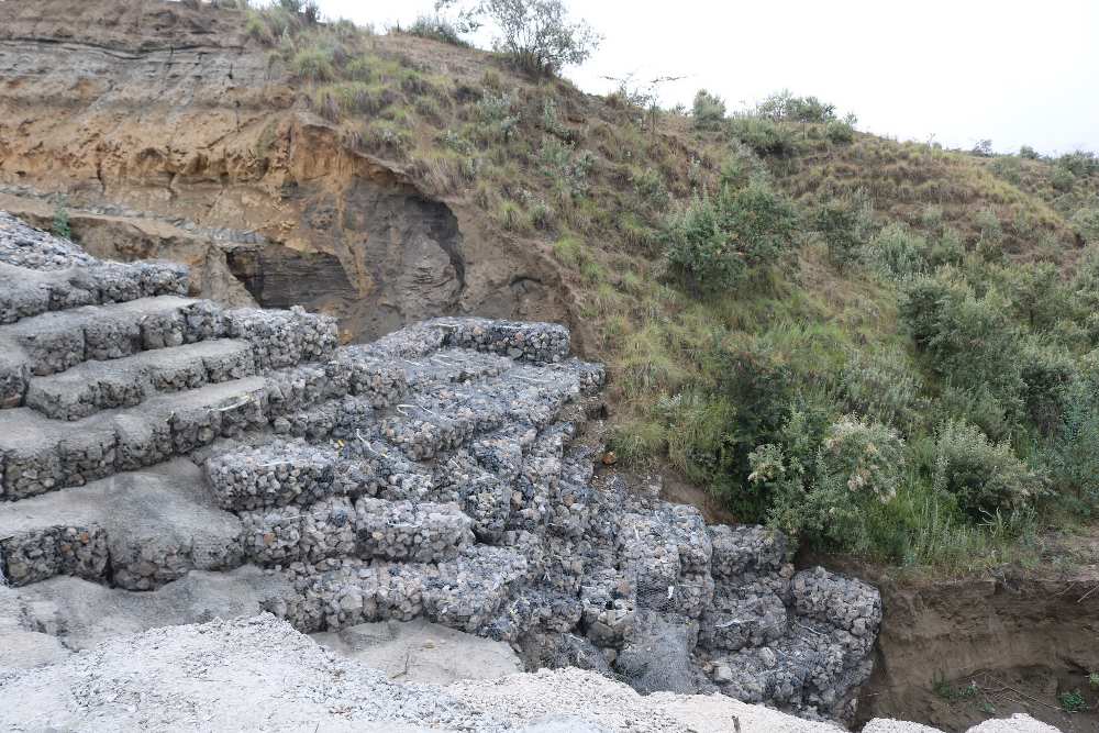 A hillside with caged rocks to protect the reaods from washing away.