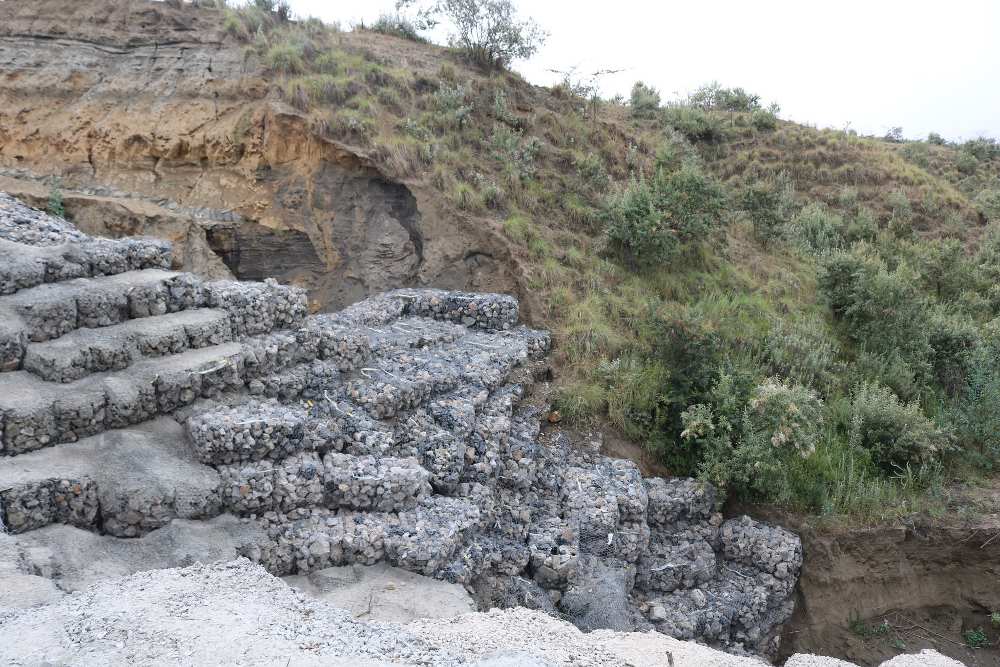 A hillside with caged rocks to protect the reaods from washing away. 