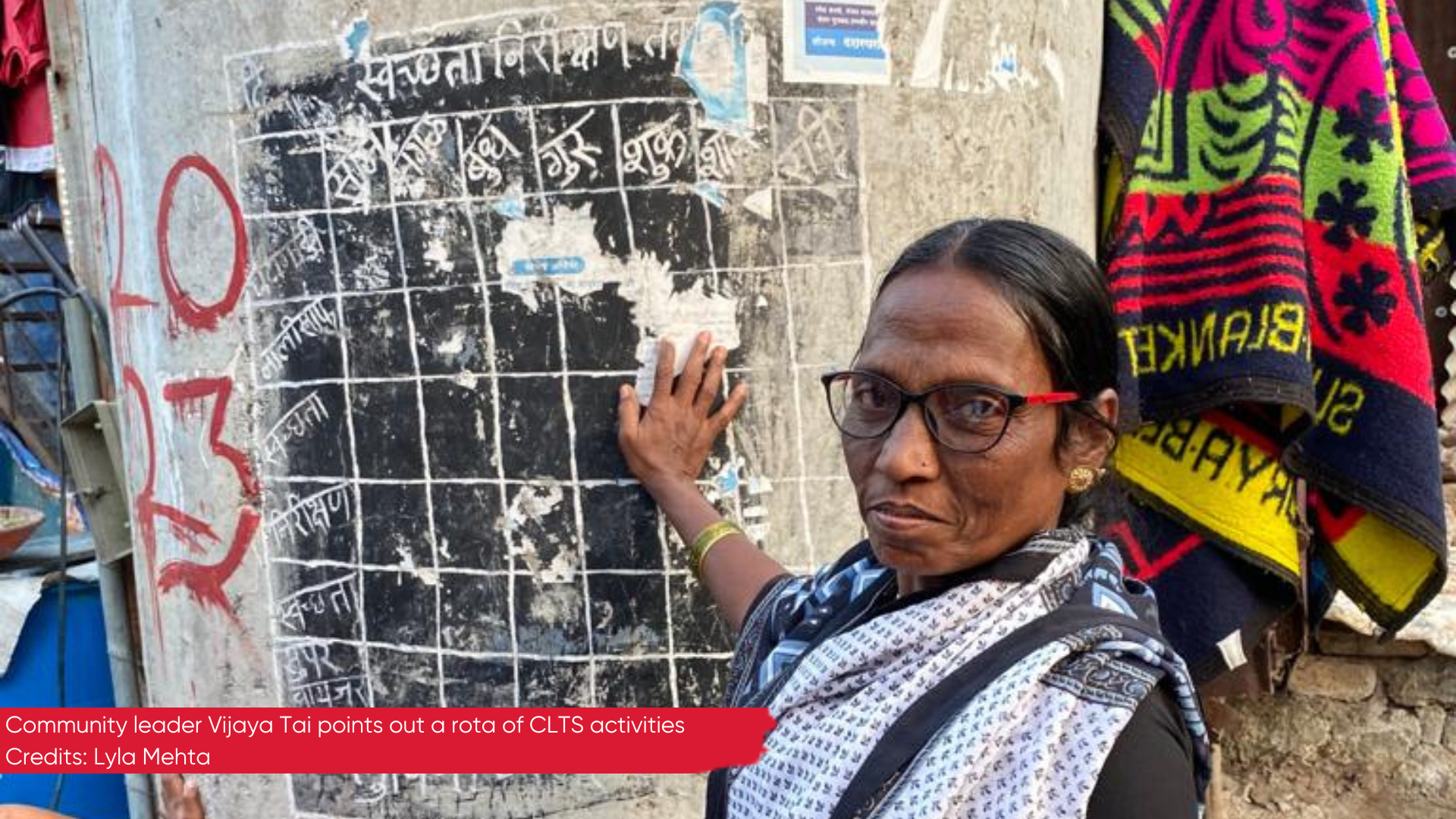 Community leader Vijaya Tai points out rota of activities during community lead sanititation