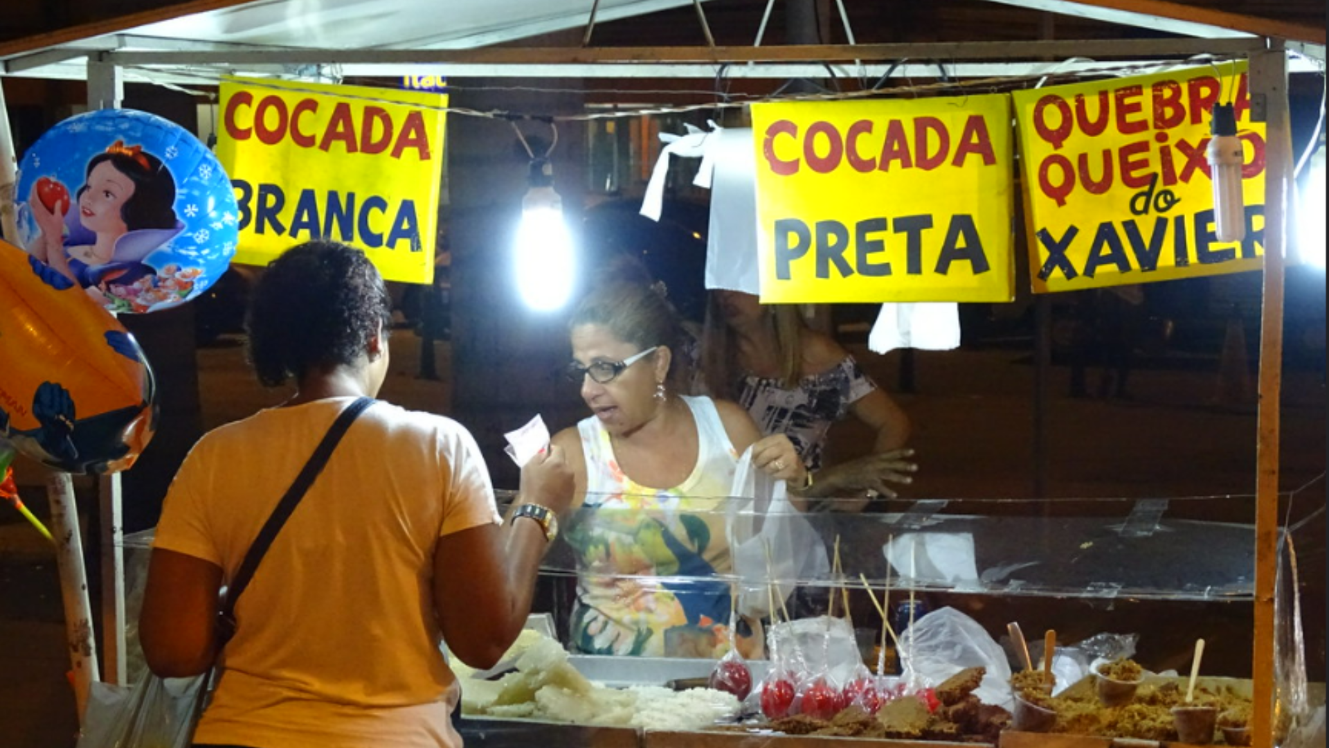 A woman buys sweet coconut from a street vendor in Brazil