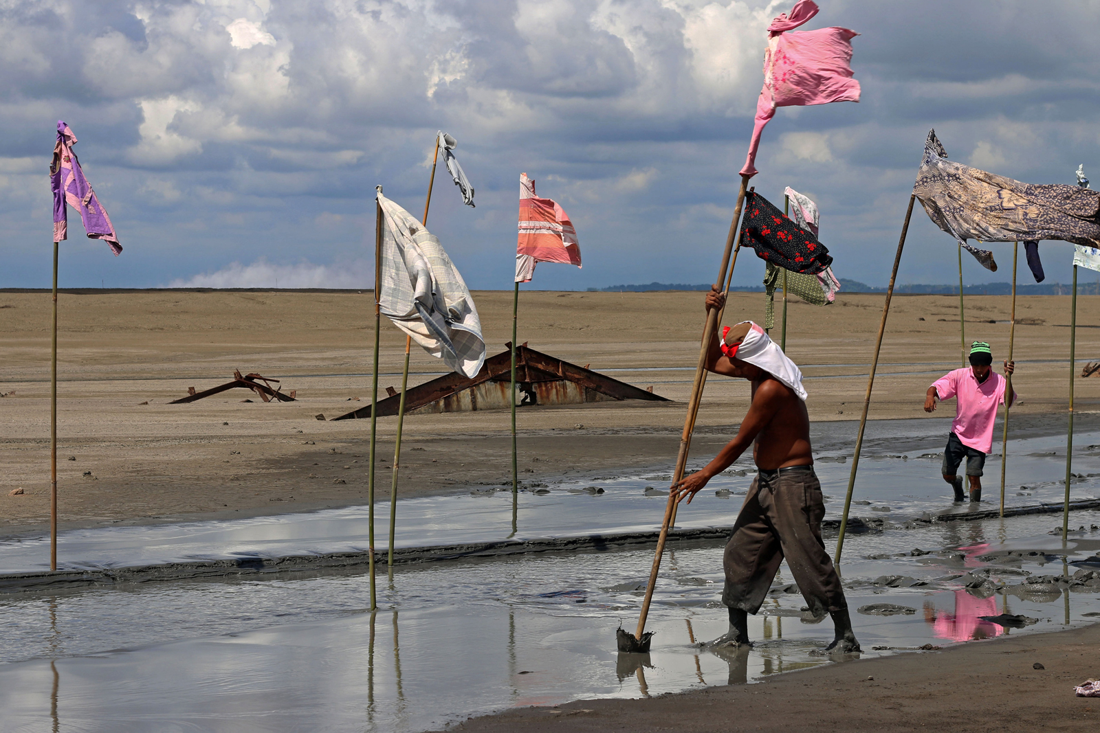 Two artists are on a beach in Sidoarjo, East Java, Indonesia putting out coloured flags into the sand.