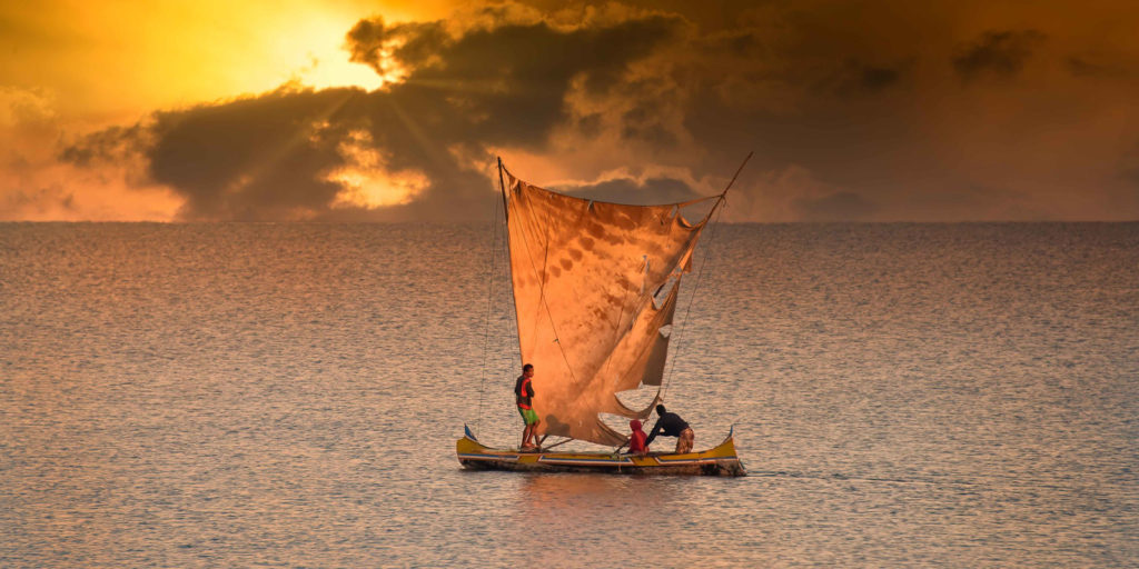 A fishing boat, with three people sailing on the sea near Madagascar