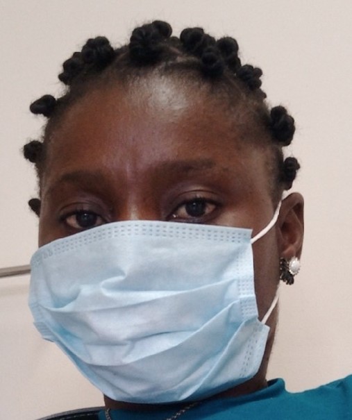 A headshot of a young Liberian woman wearing a medical face mask.