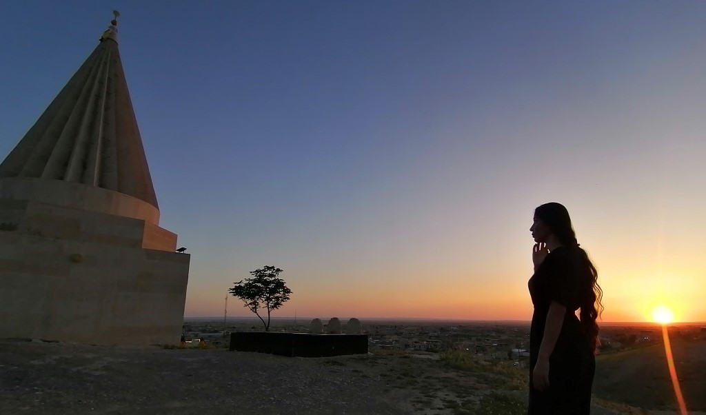 A woman outside a temple at daybreak