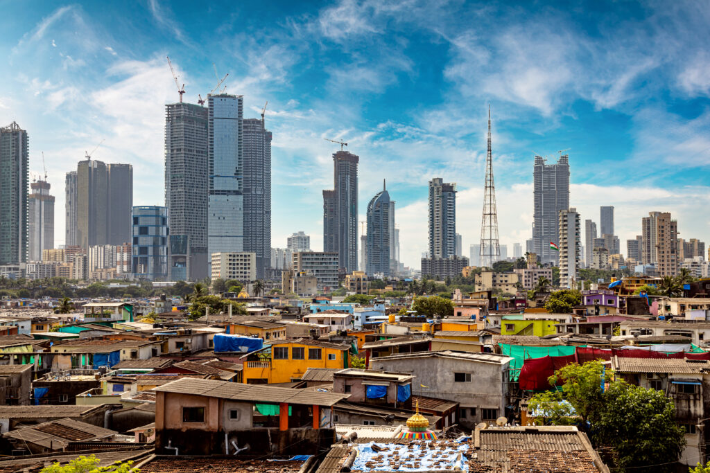 Views of slums on the shores of mumbai, India against the backdrop of skyscrapers under construction.