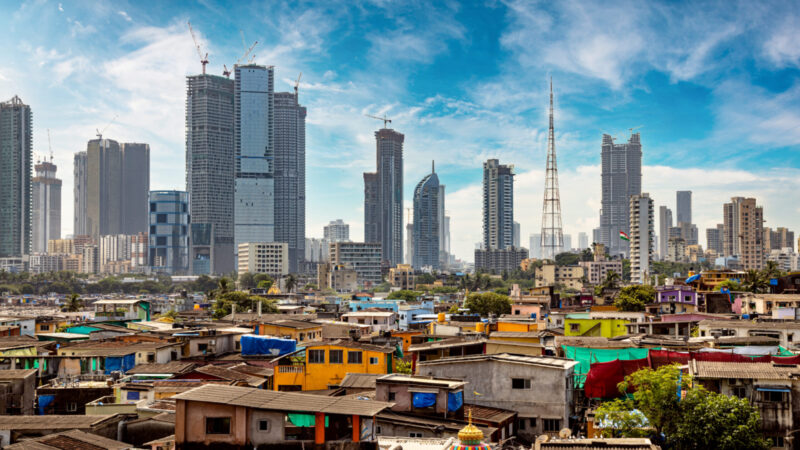 Views of slums on the shores of mumbai, India against the backdrop of skyscrapers under construction.