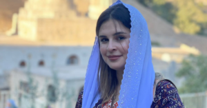 A dark-haired woman in a purple veil pictured outside a temple.