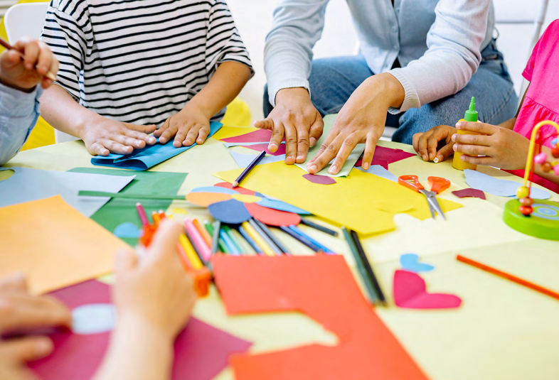A group of children sitting around a table doing arts and crafts.