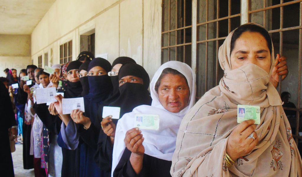 Women in Pakistan standing in a line to vote. They are holding their National Identification Cards. 