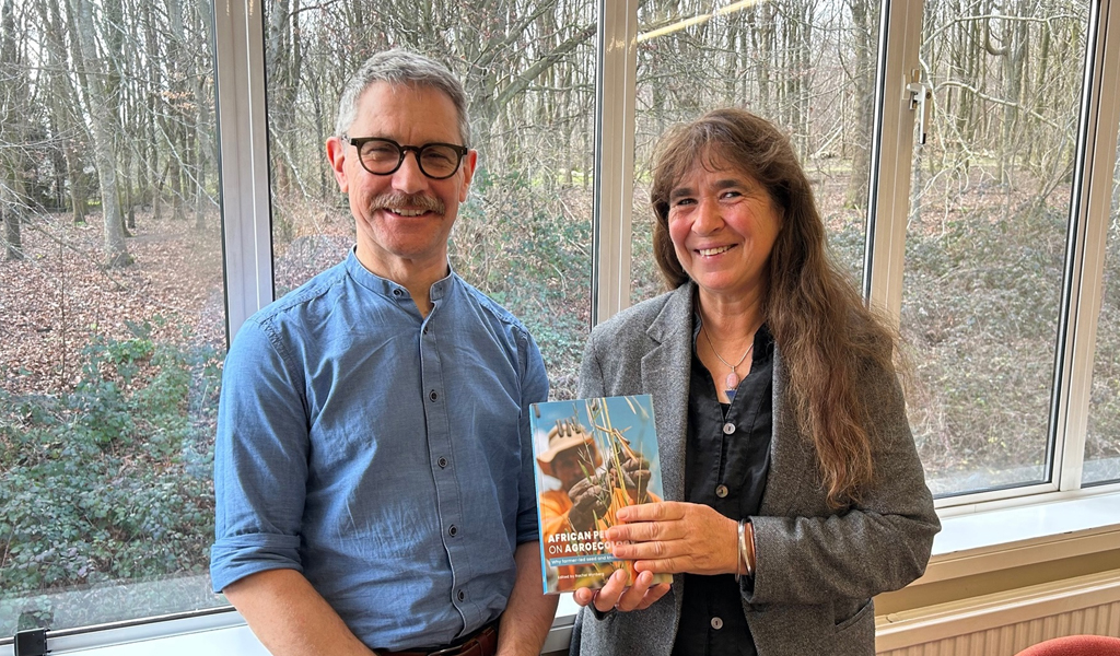 A photo of Dominic Glover and author Rachel Wynberg standing next to each other. Rachel is doling her book titled: African Perspectives on Agroecology