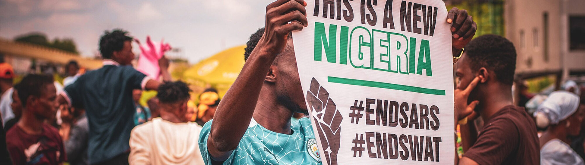 This is a photo of a Nigerian man holding up a placard with these words on them. This is a new Nigeria. #ENDSARS #ENDSWAT.