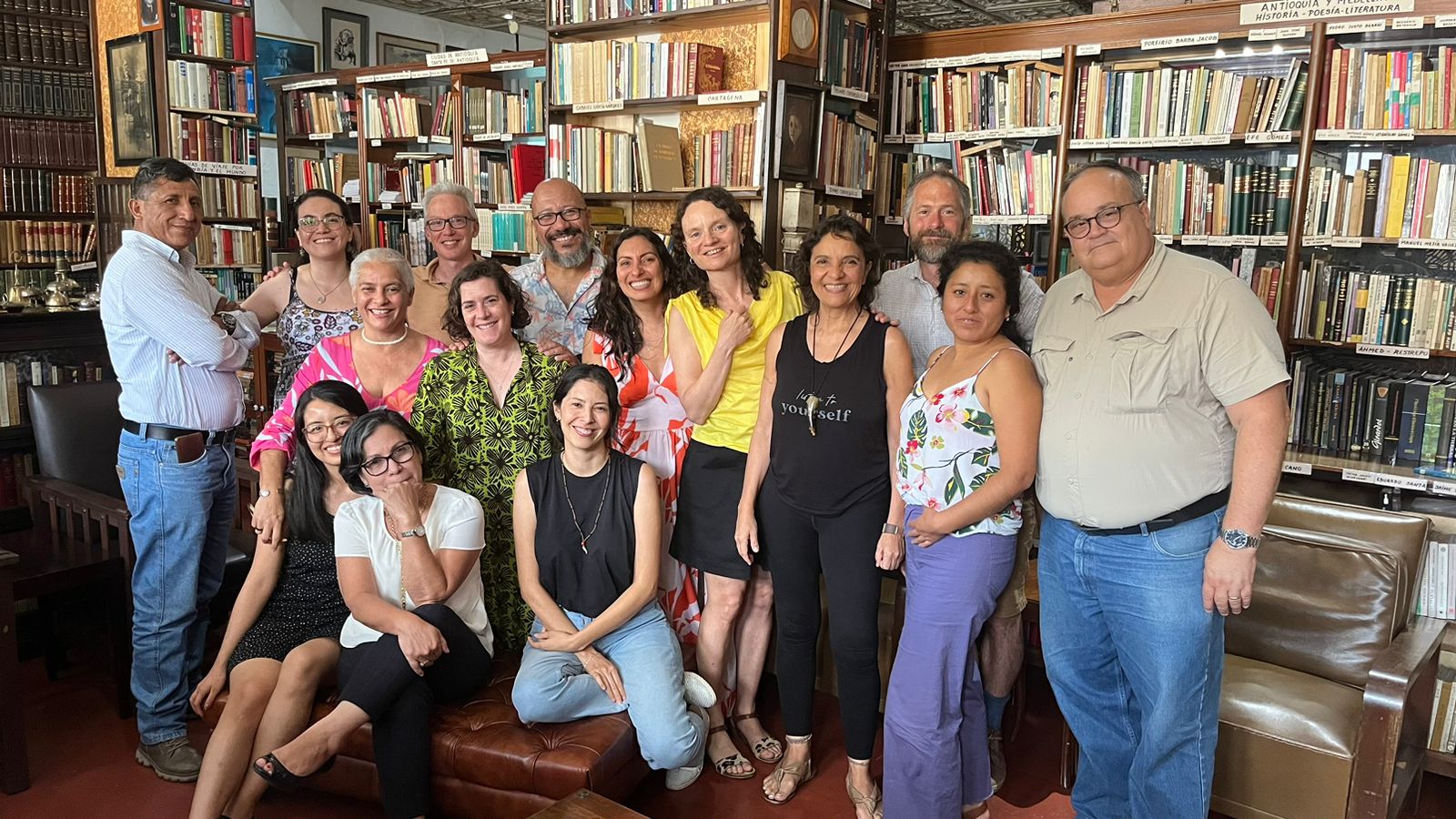 A group of 12 people smiling at the camera in front of shelves of books