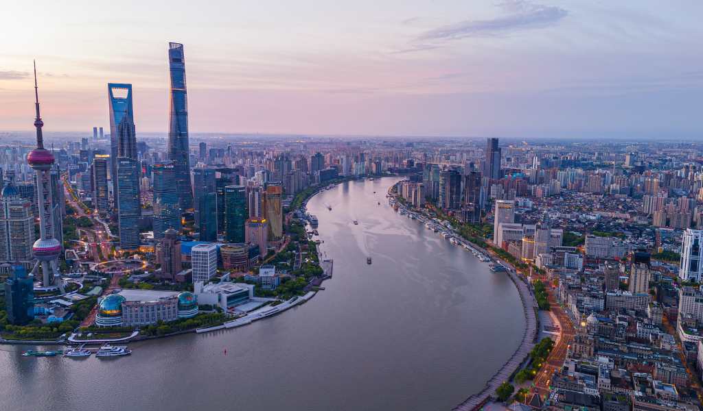 A large river bending between two sides of a city densely packed with tall buildings and skyscrapers.