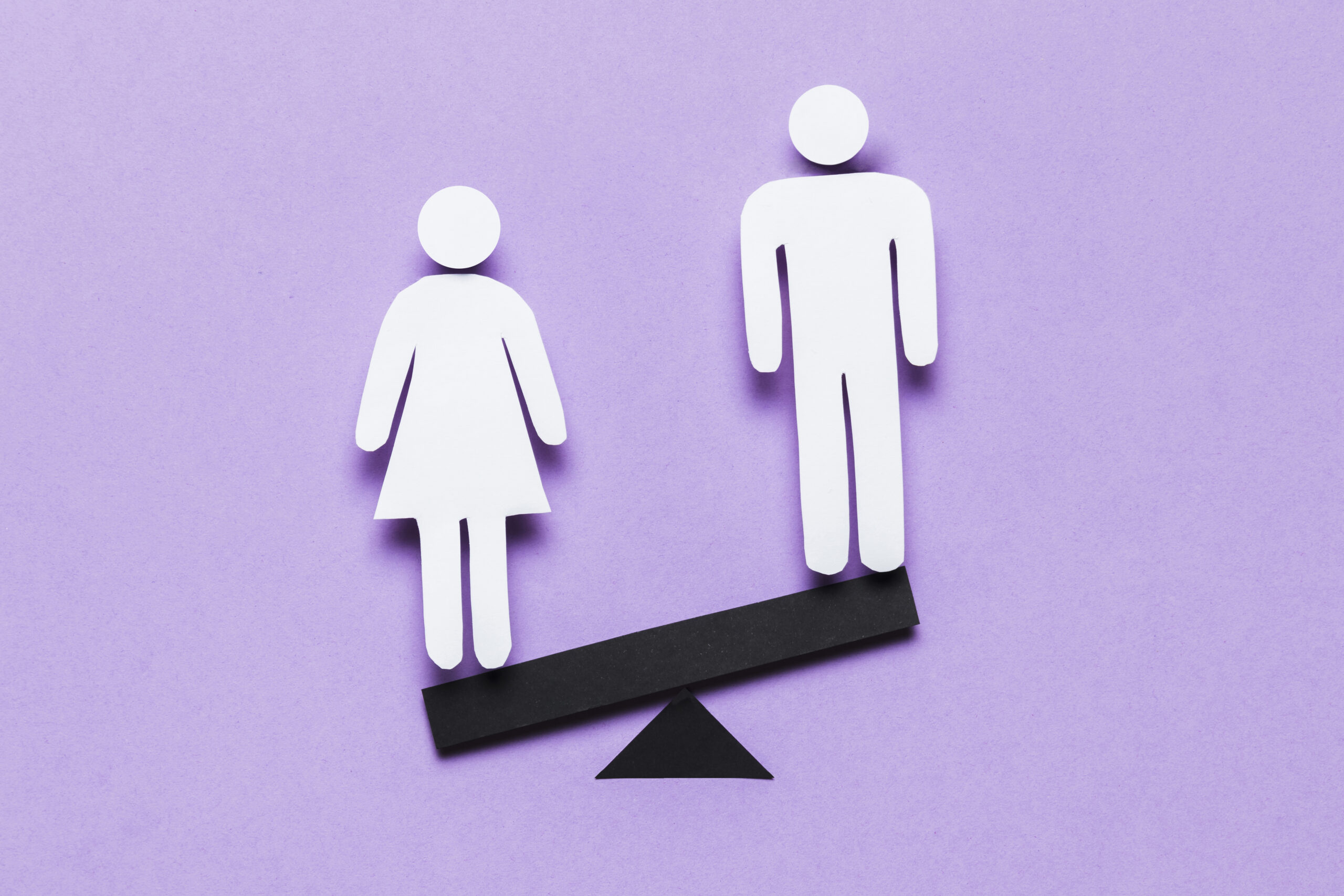 A cartoon image of a woman standing on the lower side of a seesaw opposite a man, against a light purple background.