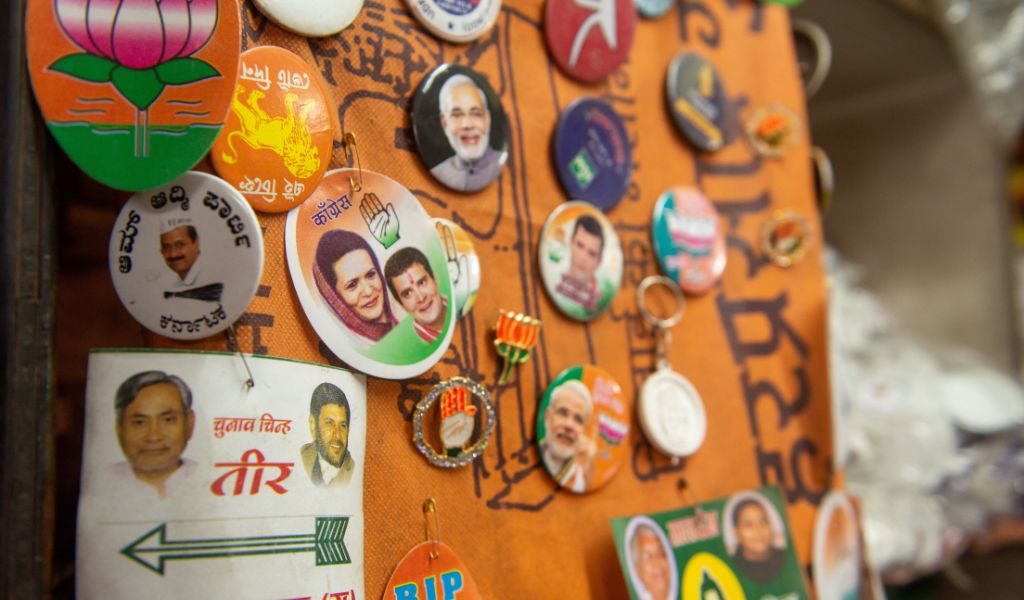 An orange piece of material displaying a selection of round pin badges of India's political parties.