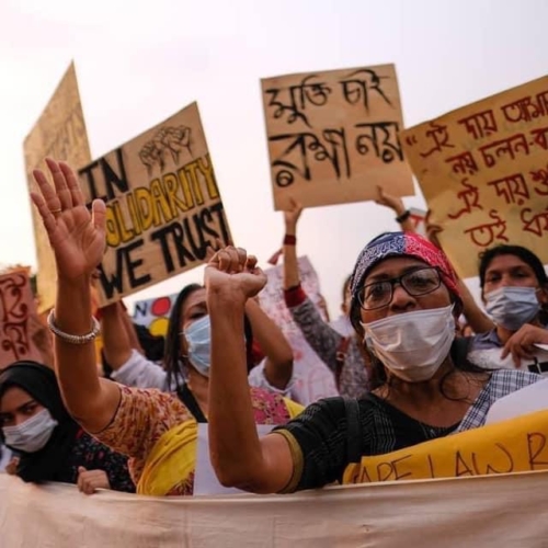 A group of women protest with raised fists and placards.