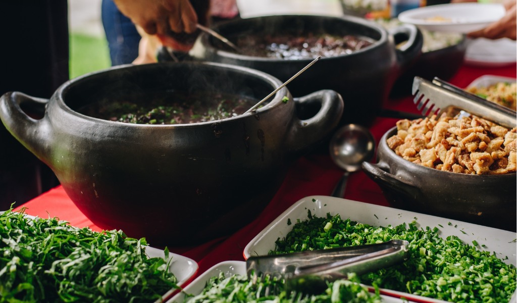 A brown bowl with food and green leaves in a bowl with brown croutons on the side