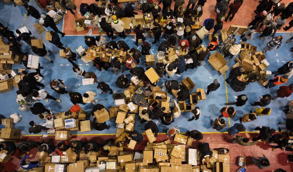 This is a photo of an overhead shot of a group of people collecting food parcels in carboard boxes.
