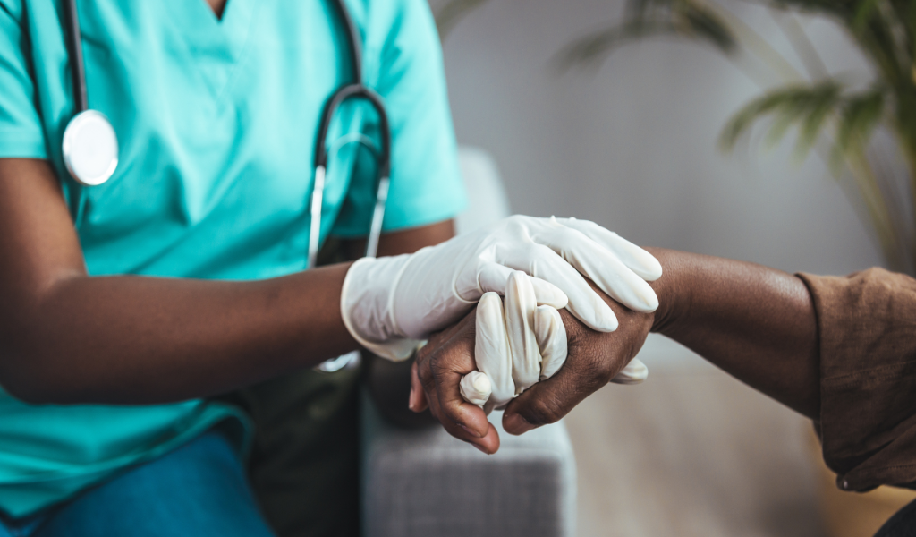 Woman holding another hand wearing white gloves and a stethoscope