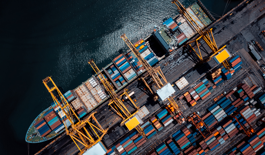 A photo of an aerial view of a shipping container on the sea. On the boat are lots of shipping containers.