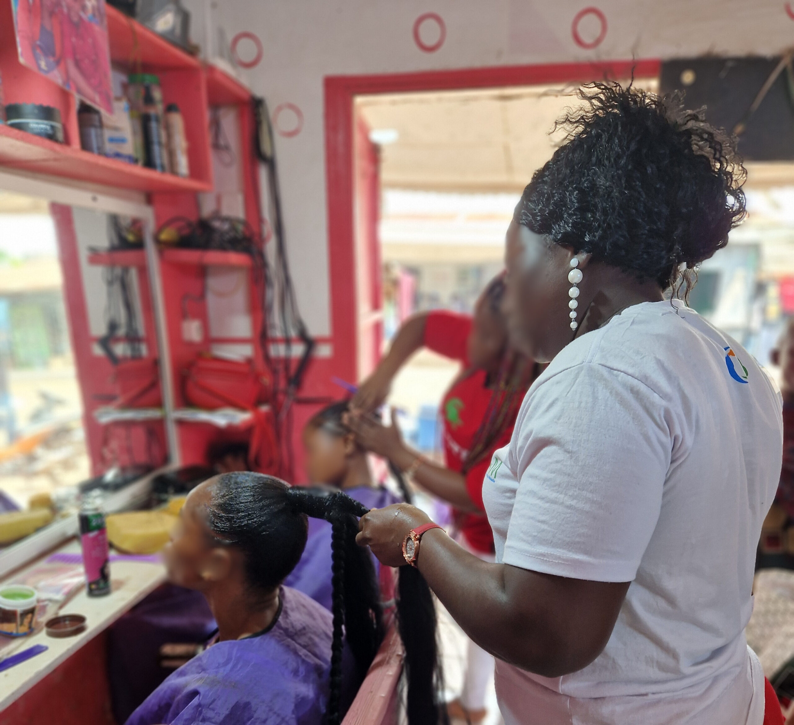 In a hair salon women braiding hair