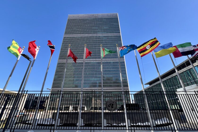 The United Nations headquarters in New York, with a row of flags of different countries in the foreground.