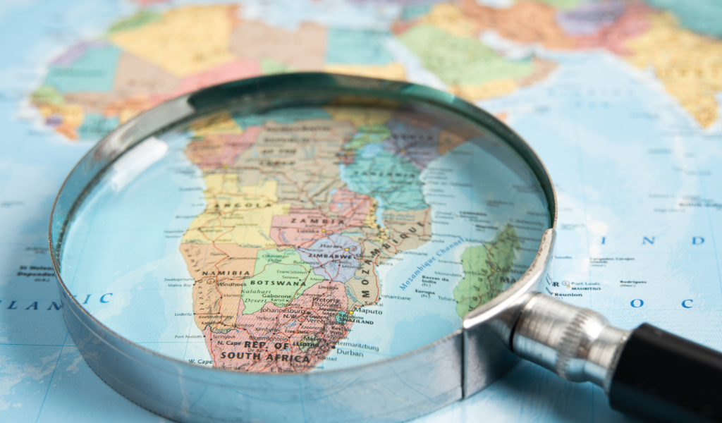 , Magnifying glass close up with colorful world map, travel, geography, tourism and exploration concept.