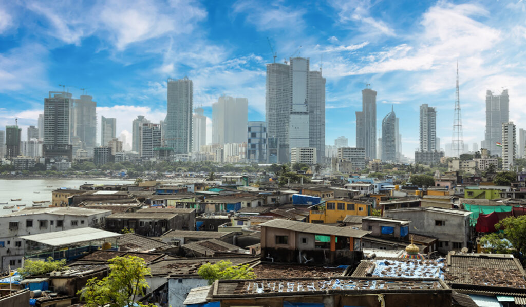 Views of slums on the shores of Mumbai, India against the backdrop of skyscrapers under construction.